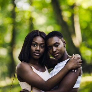A man and woman hugging in the woods.