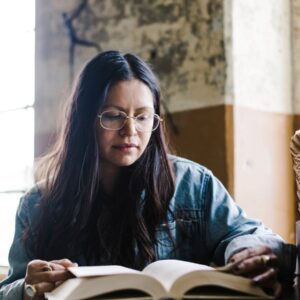 A woman sitting at a table reading a book.