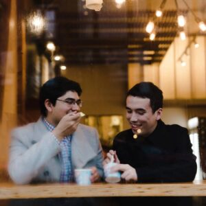Two men sitting at a table with cups of coffee.